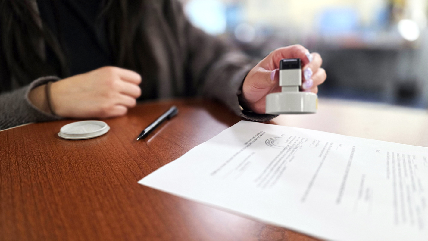 A woman stamping a document with her notary stamp.